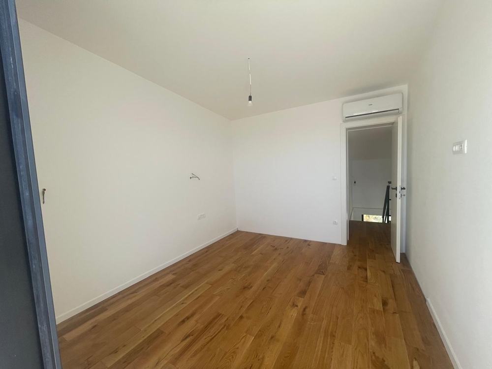 Interiér s tromi úzkymi oknami usporiadanými nad sebou, výhľad do zelene