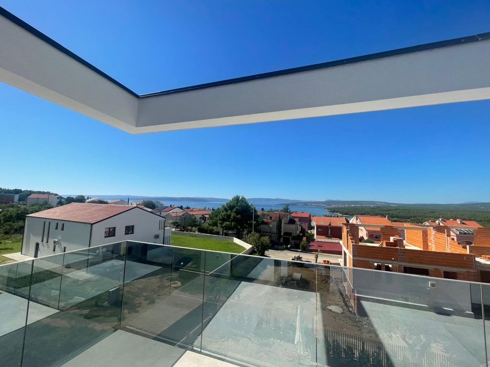 Nedokončená izba s veľkými sklenenými dverami vedúcimi na terasu s výhľadom na more, stavebné náradie v izbe