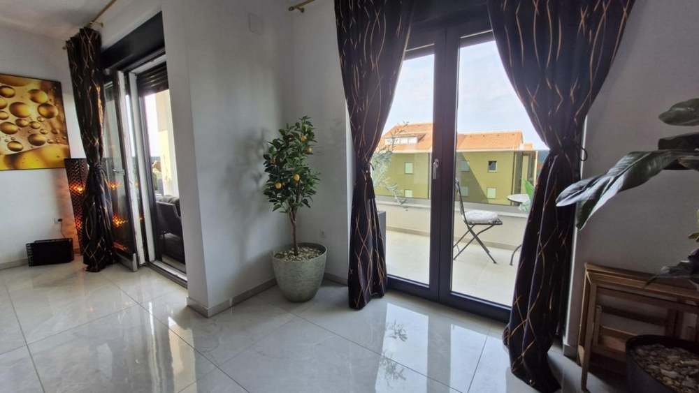 Pohľad na dvoje balkónové dvere so závesmi, črepníková rastlina v rohu