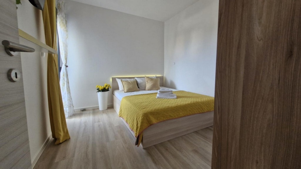 Spálňa s manželskou posteľou, žltou perinou a dekoráciami