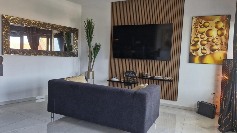 Obývacia izba s veľkou TV, pohovkou a dekoratívnymi prvkami