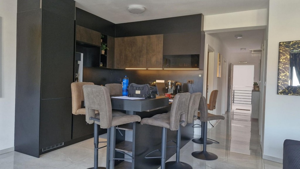 Moderná kuchyňa s barovými stoličkami a jedálenským stolom