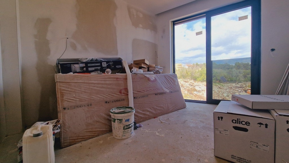 Nedokončená izba so staveniskami a veľkým oknom s výhľadom na krajinu.