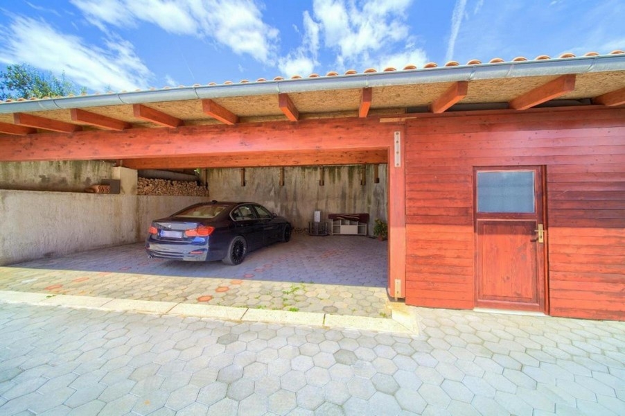 Kryté parkovisko so zaparkovaným autom a dreveným obkladom