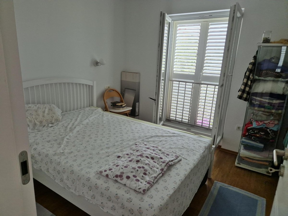 Spálňa s manželskou posteľou, bielym nábytkom a oknom