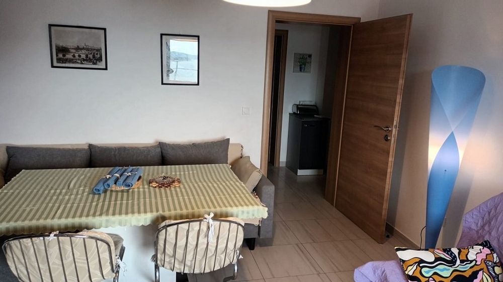 Jedálenský kút s jedálenským stolom a stoličkami, vedľa pohovky a otvorenými dverami na chodbu.