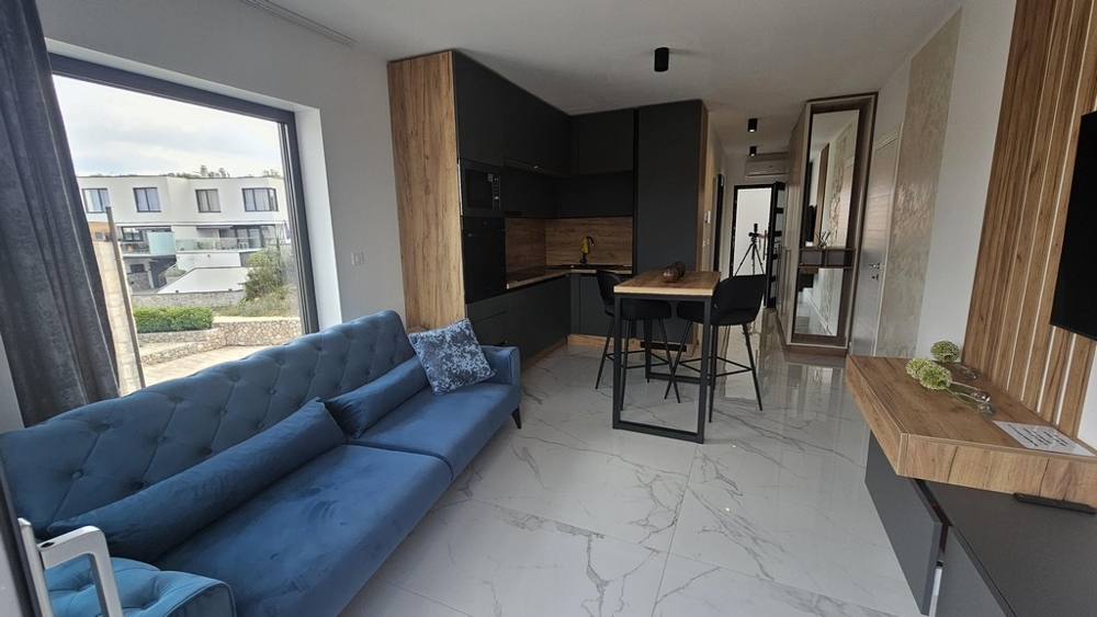 Obývacia izba s pohovkou, priľahlá kuchyňa a balkón