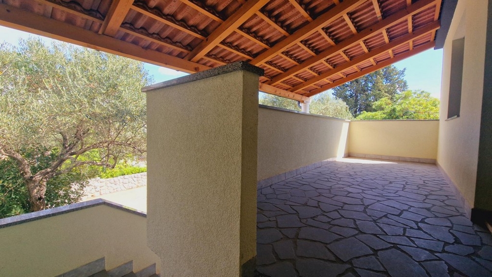 Krytý vonkajší priestor s kamennou podlahou, výhľadom na stromy a prírodu.