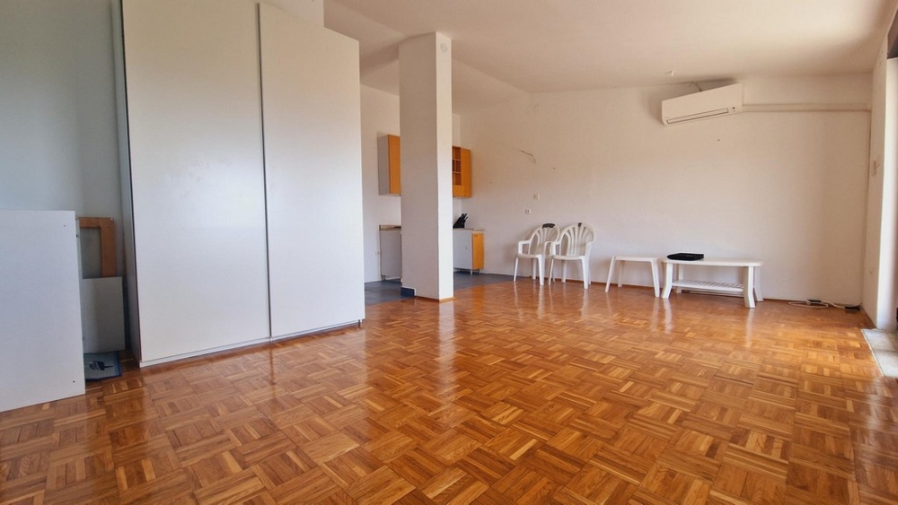 Priestranná obývacia izba s parketovými podlahami, klimatizáciou a minimalistickým nábytkom.