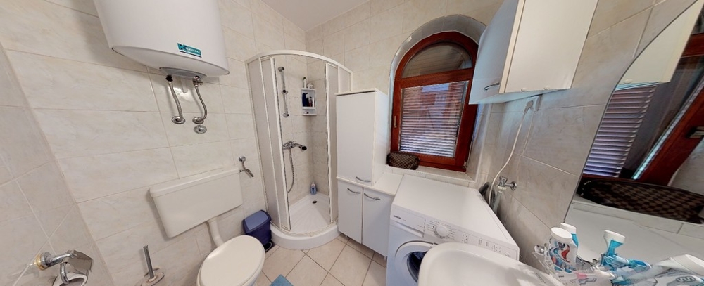 Svetlá kúpeľňa s oknom a sprchovacím kútom.