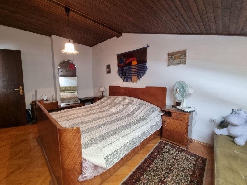 Spálňa s veľkou posteľou, dreveným stropom a kobercom.