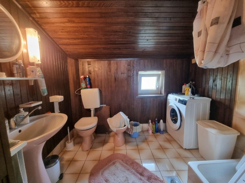 Kúpeľňa s tmavým dreveným obkladom a práčkou.