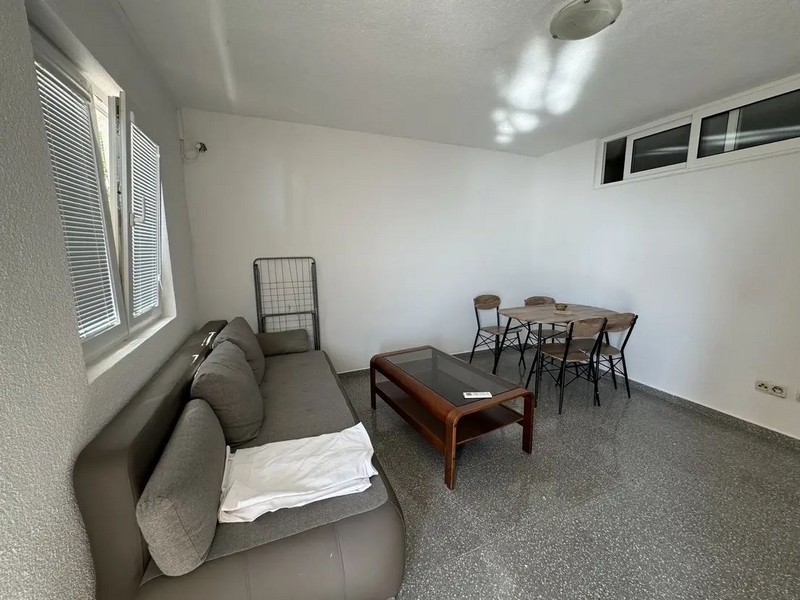 Obývacia časť s gaučom a jedálenským stolom.