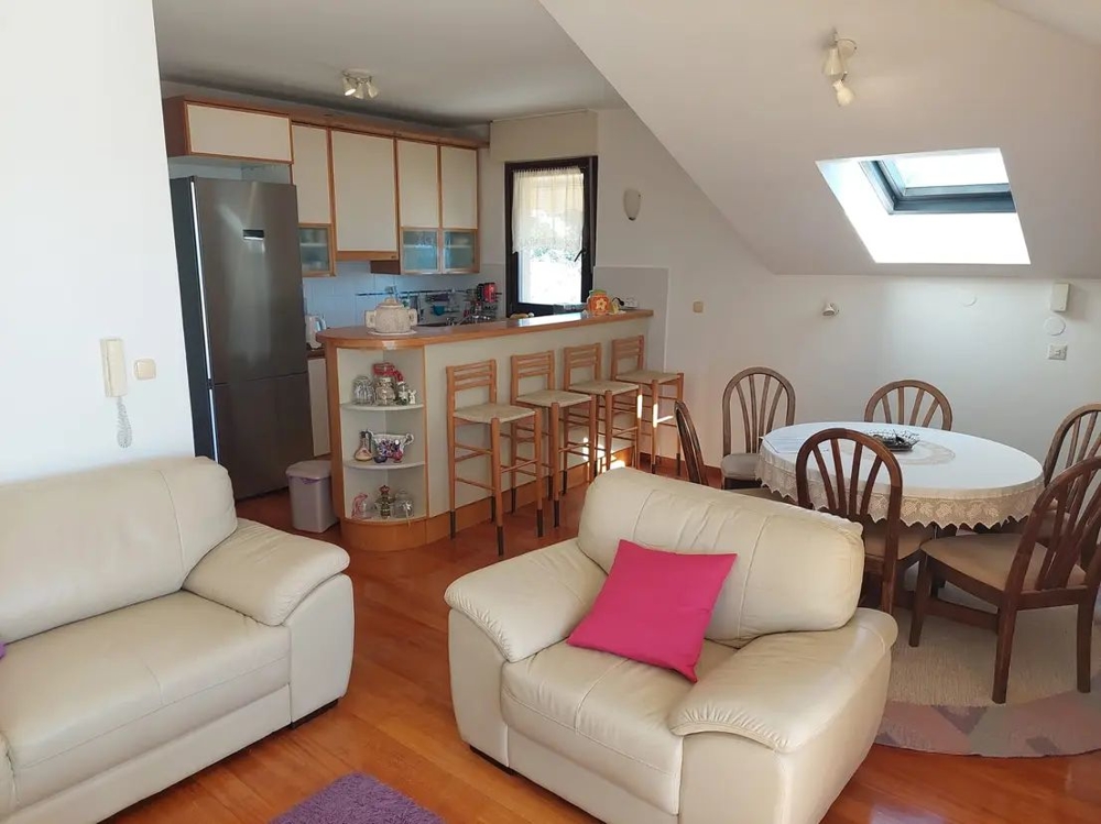 Útulná obývačka s kuchyňou, barovým pultom a jedálenským stolom v podkrovnom byte