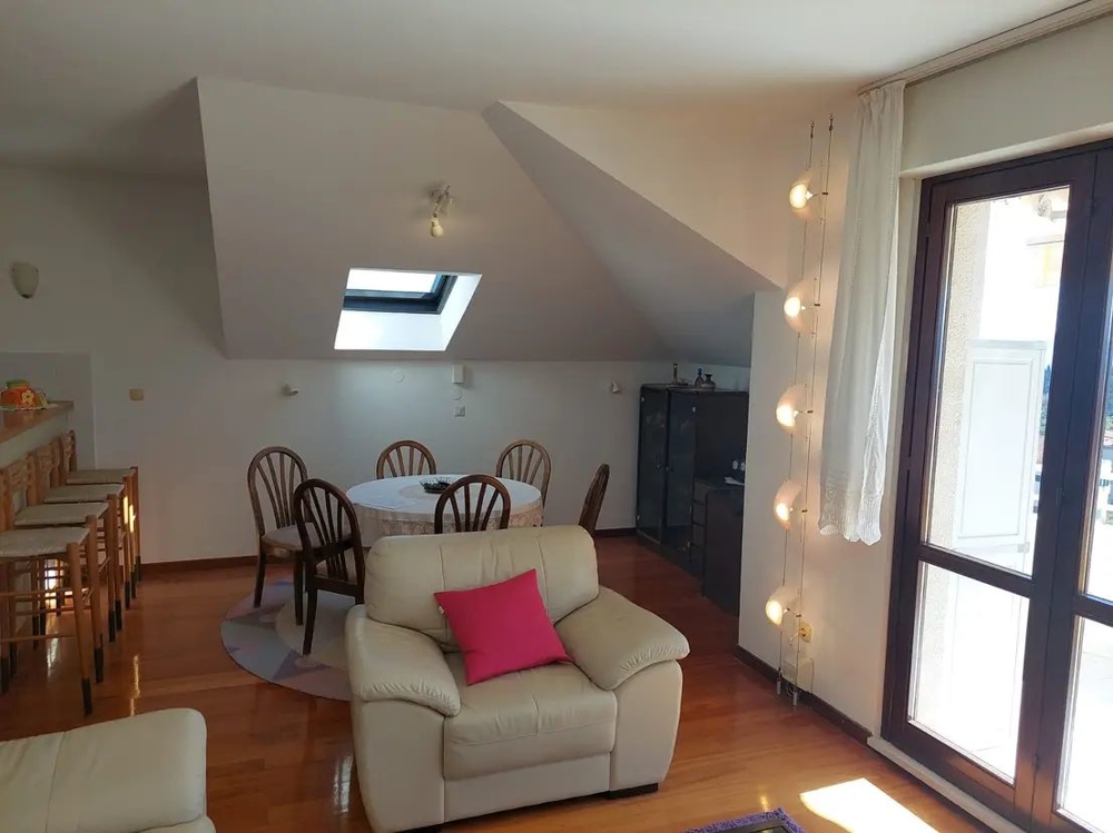 Jedálenský stôl v podkrovnom byte, veľké okná a barové stoličky pri kuchynskej linke