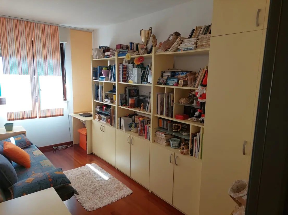 Izba s policami, písacím stolom a pohovkou, svetlými oknami