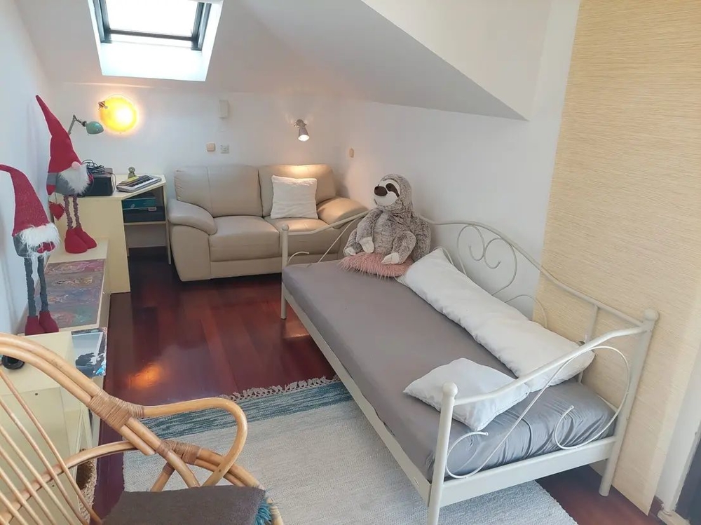 Izba s posteľou, pohovkou, strešným oknom a dekoráciami vrátane plyšových zvieratiek