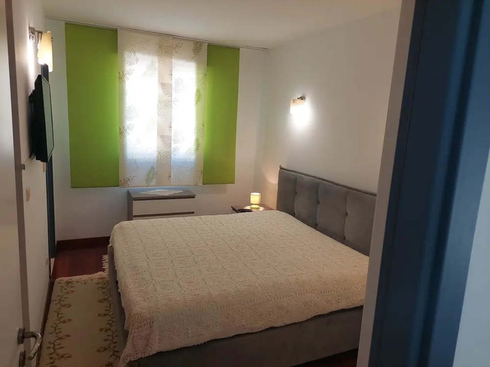 Spálňa s veľkou posteľou a zelenými závesmi