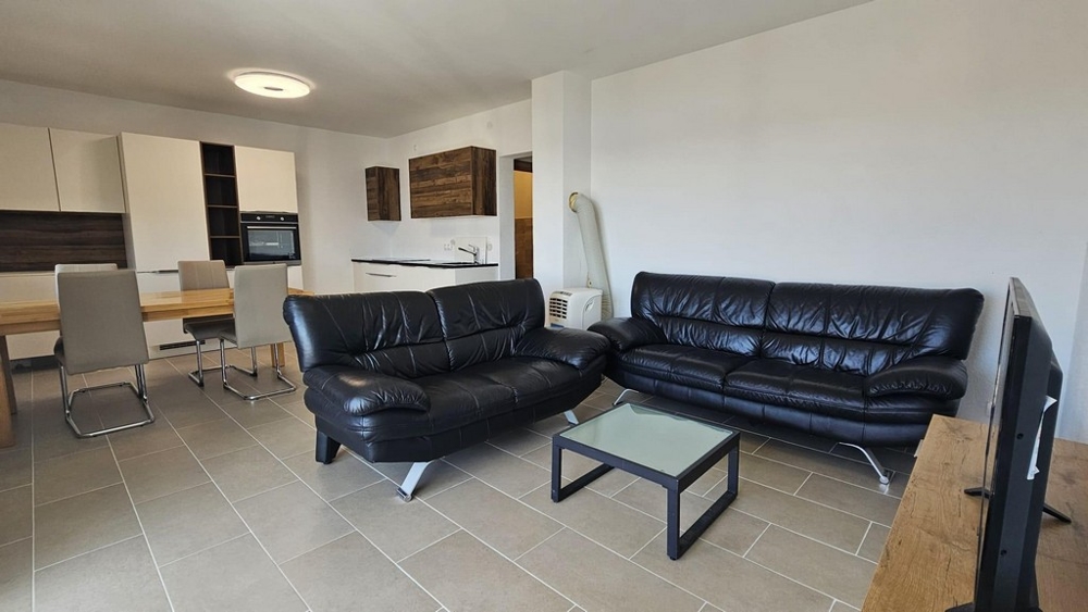 Zariadený obývací priestor a výhľad do kuchyne v byte A3475.