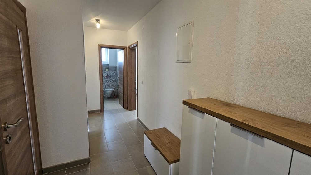 Chodba vedúca do kúpeľne s dlažbou a drevenými prvkami.