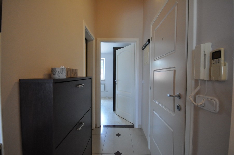 Chodba s bielymi dverami, tmavá skriňa a interkom na stene, prístup do rôznych miestností