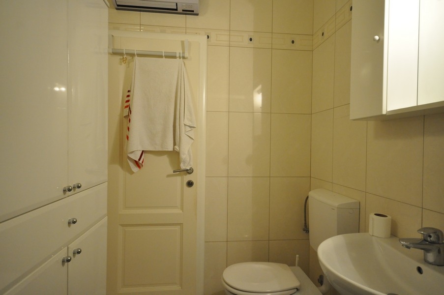 Kúpeľňa s WC, umývadlo, vešiak na uteráky na dvere, svetlá dlažba, moderné vybavenie