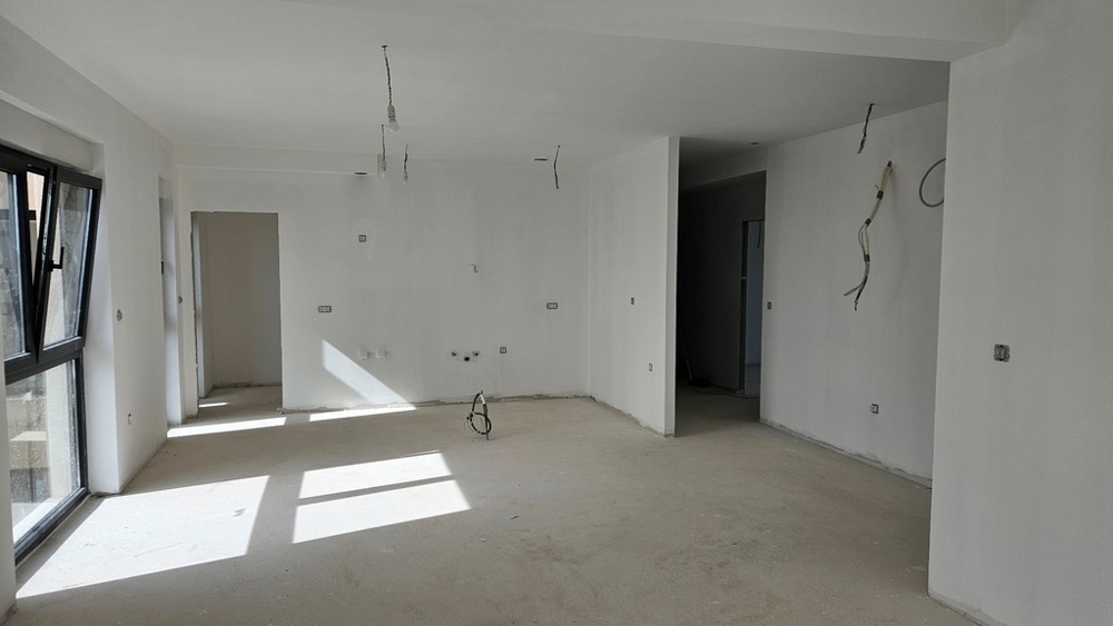 Nedokončená obývacia časť s otvorenými oknami a pripravenými prípojkami na kuchyňu