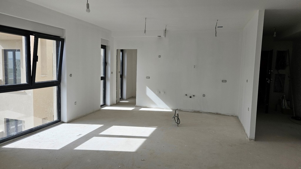 Nedokončený interiér s množstvom prirodzeného svetla, prístupný cez veľké okná
