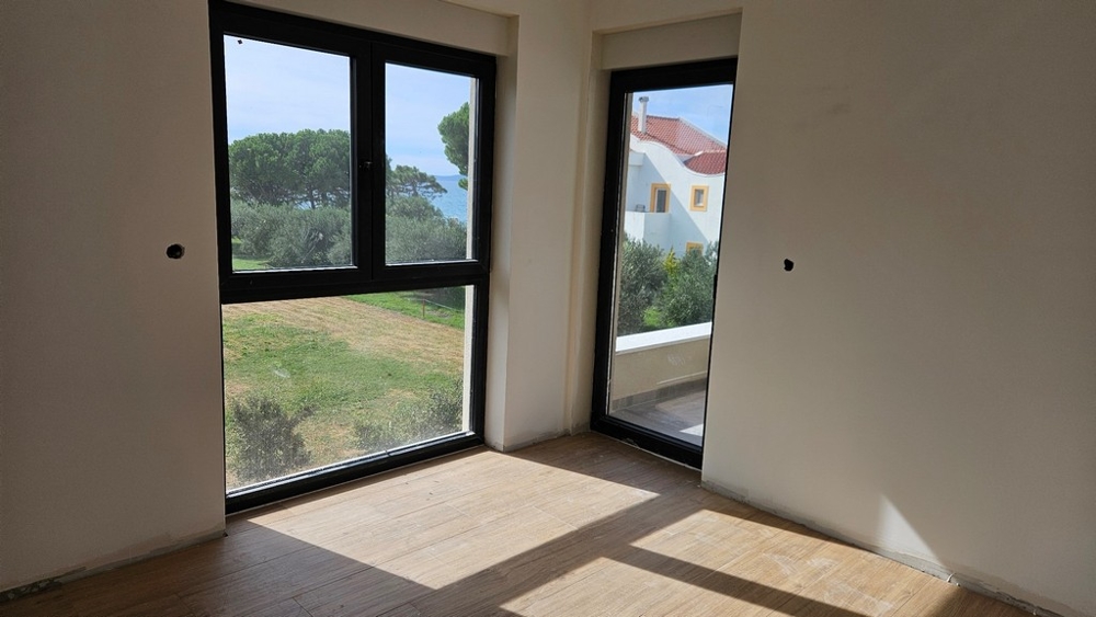 Svetlý priestor s veľkými oknami, ktoré ponúkajú výhľad na more a okolitú prírodu.