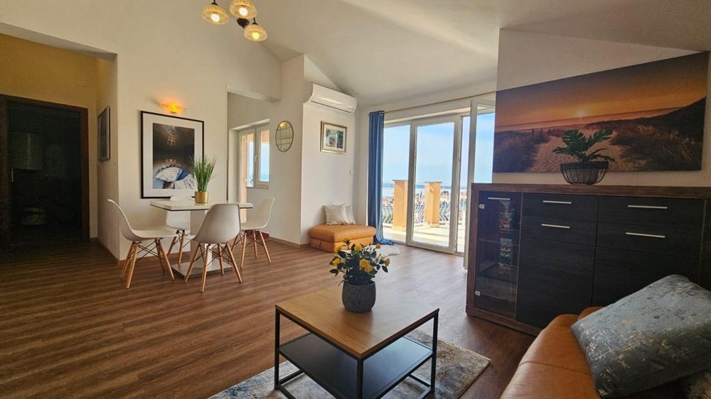 Obývacia izba s jedálenským kútom a prístupom na terasu, zdobená rastlinami a nástennými maľbami