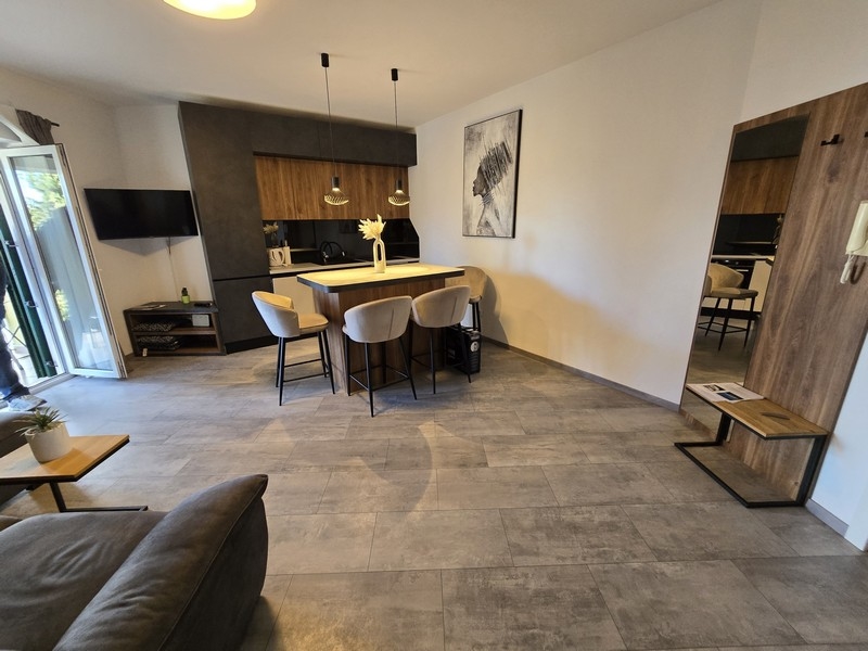 Moderná otvorená kuchyňa-obývacia izba s jedálenským kútom a štýlovými závesnými lampami v apartmáne v Opatiji.