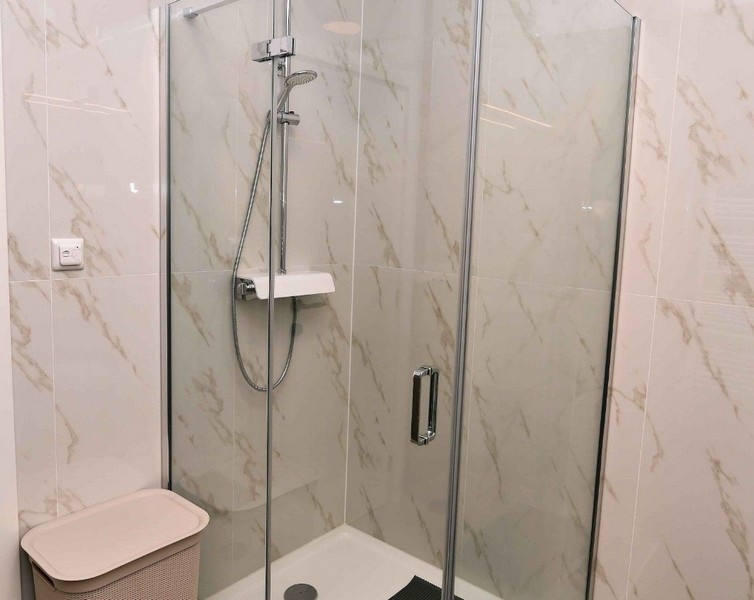 Sprchový kút s presklenými dverami a modernou batériou v kvalitnom byte.