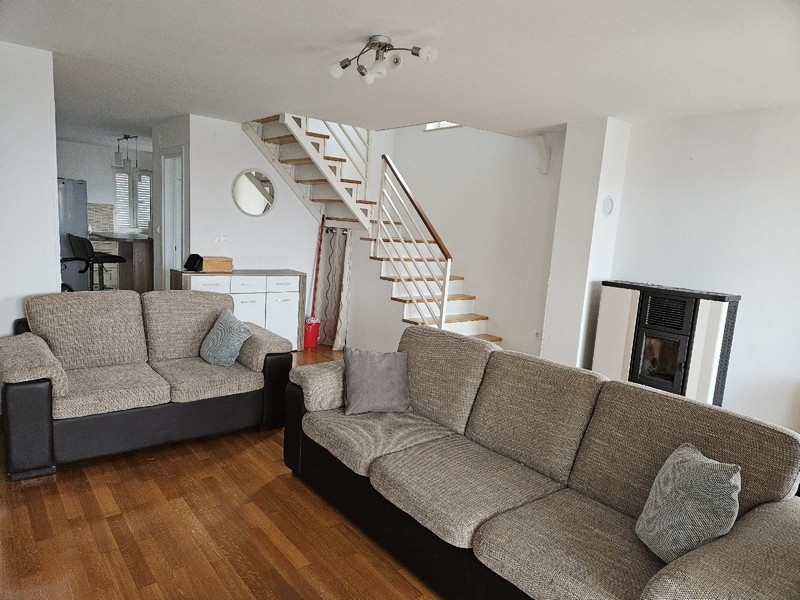 Obývacia izba so sedacou súpravou, schodiskom a pecou na pelety