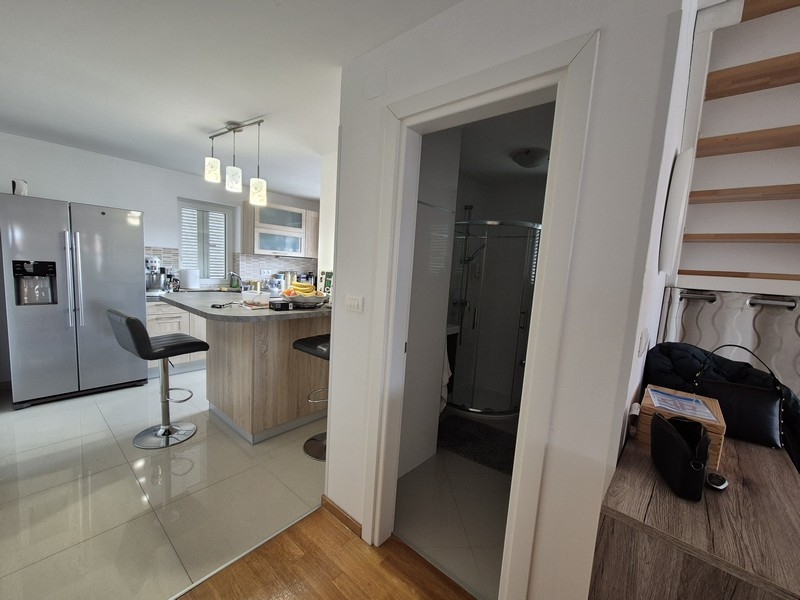 Otvorená kuchyňa s ostrovčekom, barovými stoličkami a prístupom do kúpeľne