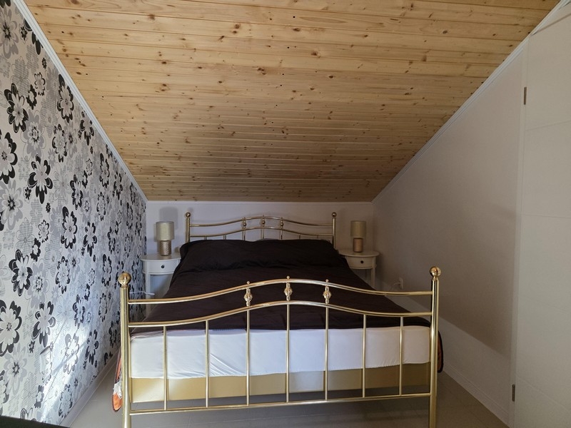 Spálňa v podkroví so šikmým stropom a manželskou posteľou