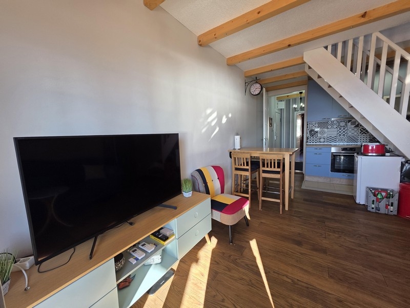 Obývacia izba s TV, jedálenským stolom a otvorenou kuchyňou