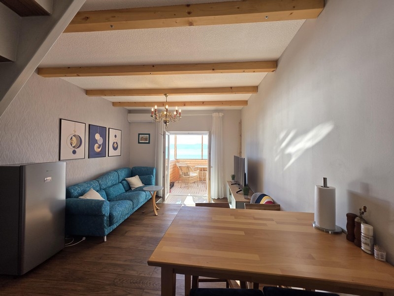 Obývacia izba s pohovkou a výhľadom na more z balkóna