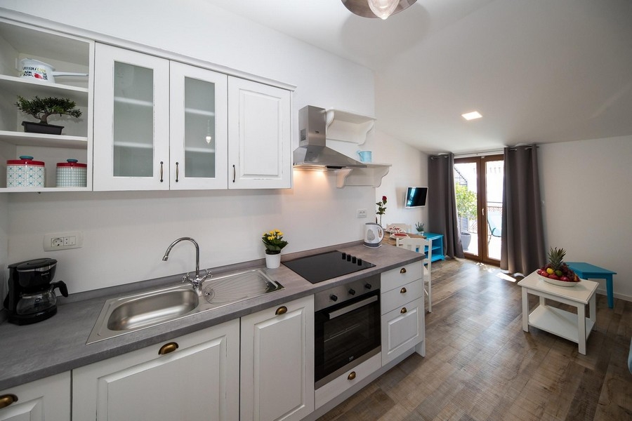 Moderná kuchyňa s bielymi skrinkami a šedou doskou