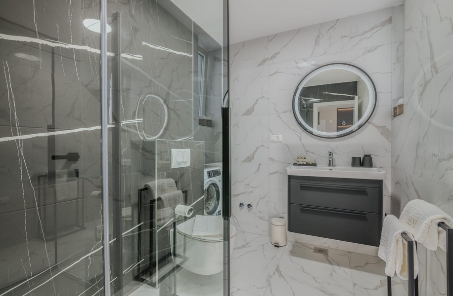 Kúpeľňa s moderným skleneným sprchovacím kútom a mramorovými obkladmi