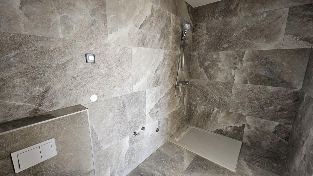 Priestranná kúpeľňa s moderným sprchovacím kútom