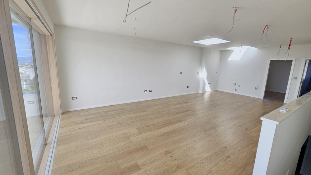 Otvorený obývací priestor s veľkými oknami a vstupom na balkón