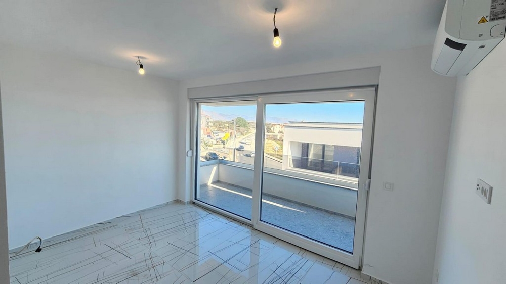 Druhá spálňa so vstupom na balkón a výhľadom na obytný komplex