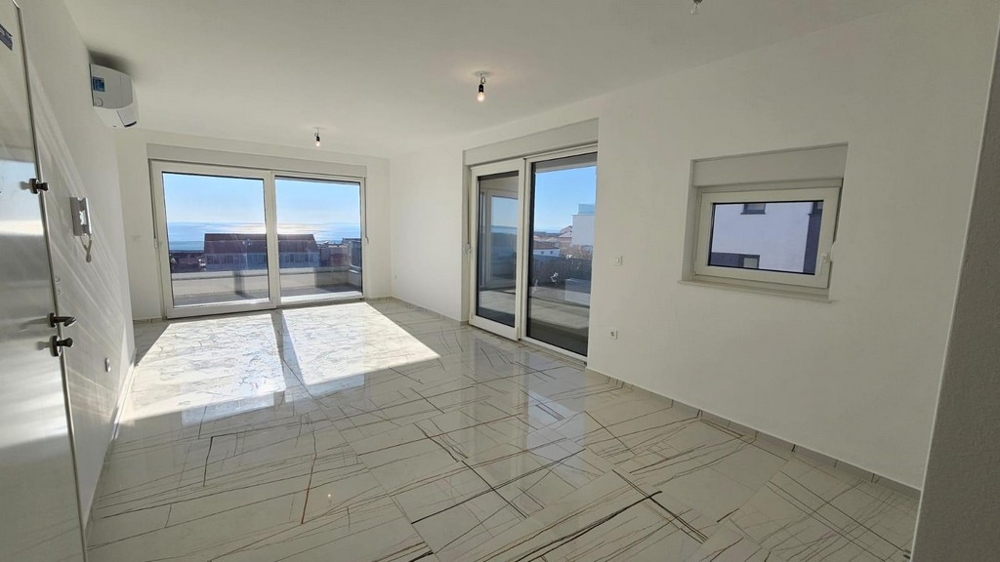 Svetlá obývacia izba s veľkými oknami a výhľadom na more