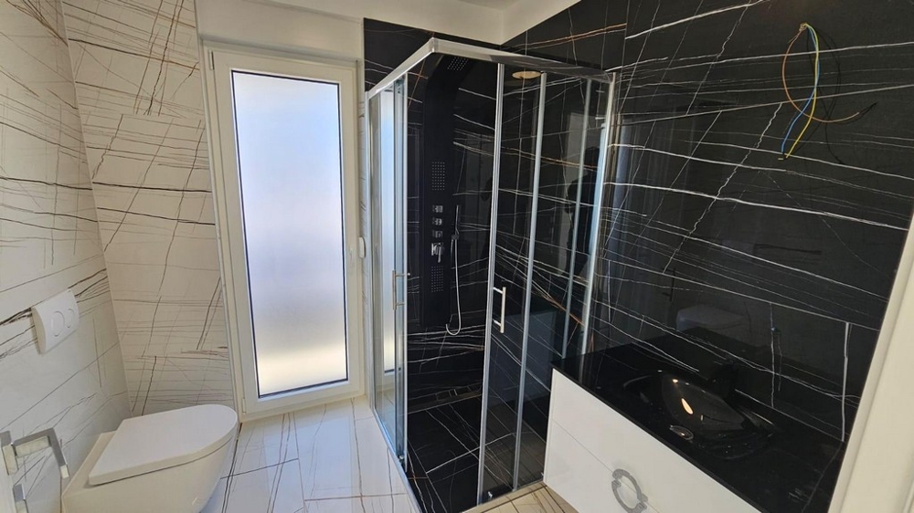 Štýlová kúpeľňa so sprchovacím kútom a tmavými obkladmi