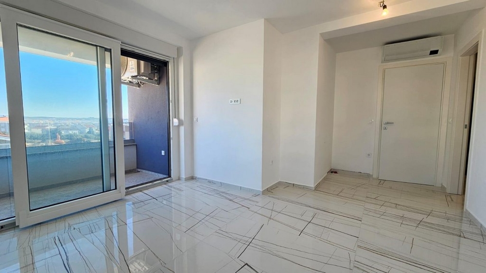 Svetlá obývacia izba s prístupom na balkón a výhľadom na more