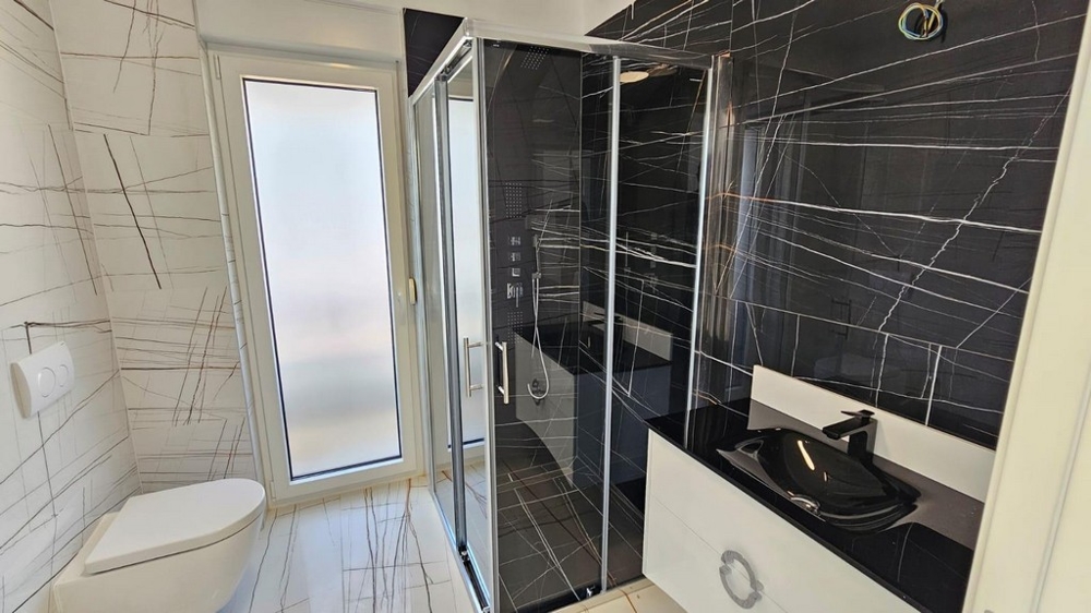 Elegantná kúpeľňa s čiernym sprchovacím kútom a umývadlom