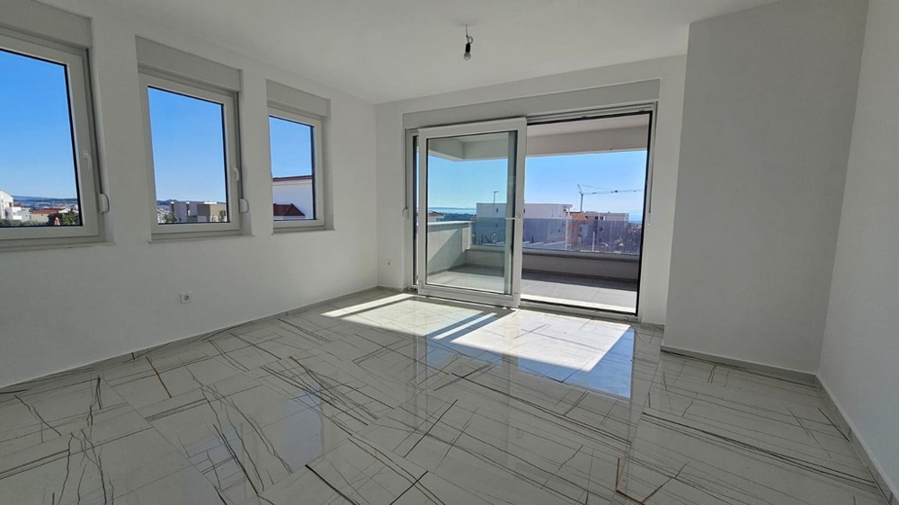 Svetlá obývacia izba s balkónom a výhľadom na more.