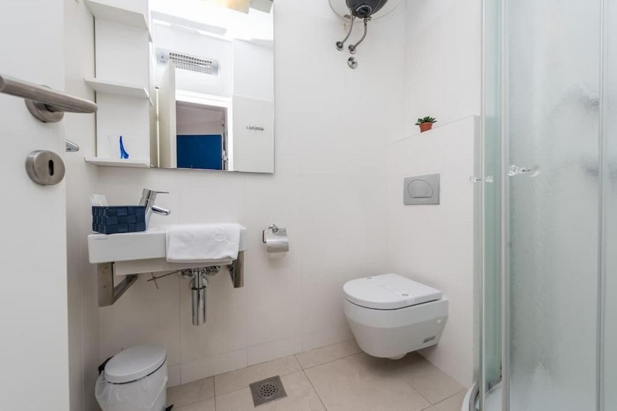 Kúpeľňa so sprchovacím kútom a bielymi obkladmi