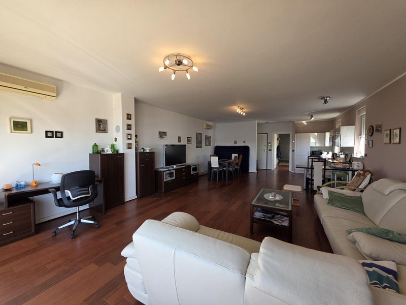 Svetlá obývacia izba s parketovými podlahami, koženou pohovkou a výhľadom na more