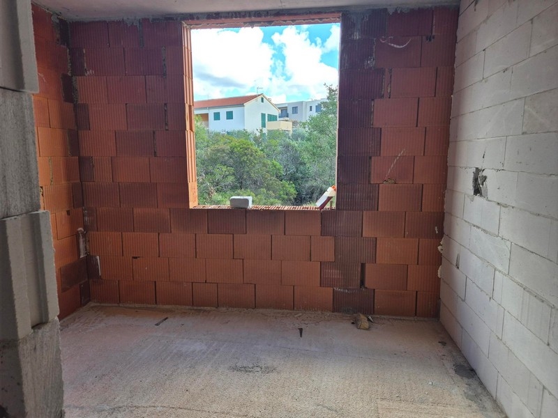 Nedokončený obytný priestor s výhľadom na susedné domy cez veľké okno